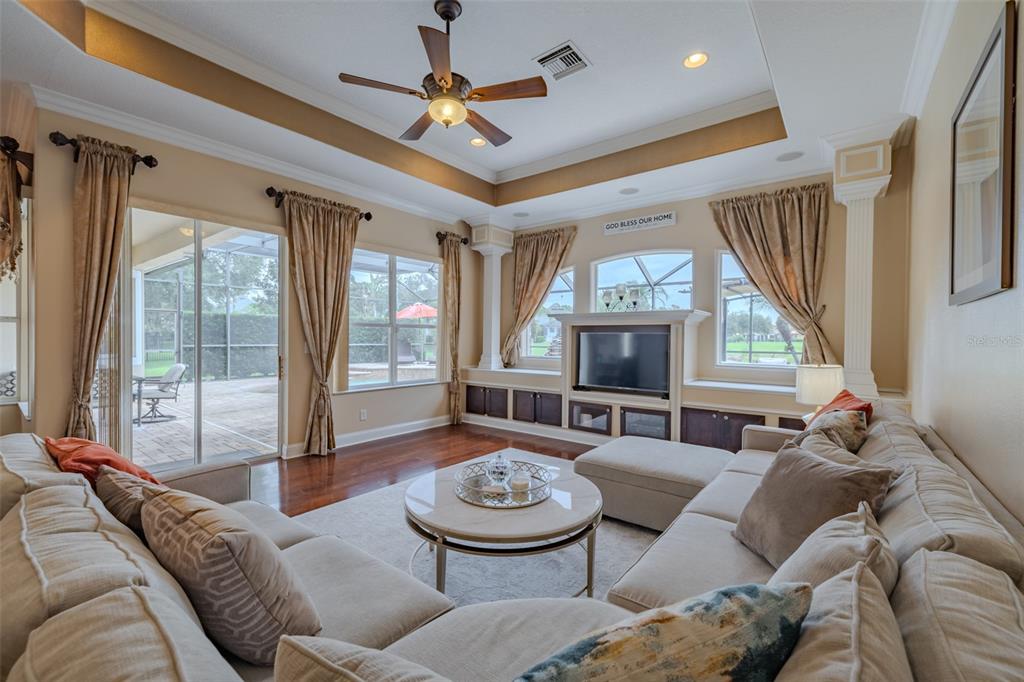 A living room features a sectional sofa, a coffee table, built-in cabinetry, and sliding glass doors — 8016 CYPRESS CROSSING COURT, TAMPA, FL