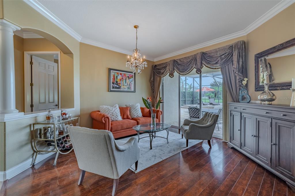 A living room features an orange sofa, two armchairs, a glass coffee table, and hardwood floors — 8016 CYPRESS CROSSING COURT, TAMPA, FL