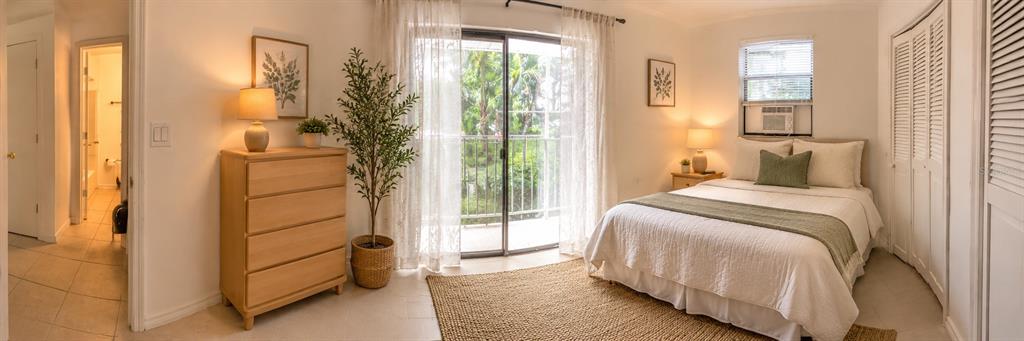 A bedroom features a bed, a wooden dresser, a balcony door, and an attached bathroom — 1735 TIMOCUAN WAY UNIT B, LONGWOOD, FL