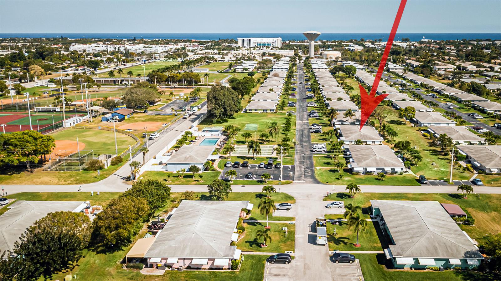 An aerial view shows a residential community with rows of single-story buildings and a red arrow — 310 Main Boulevard # C, Boynton Beach FL 33435, BOYNTON BEACH, FL