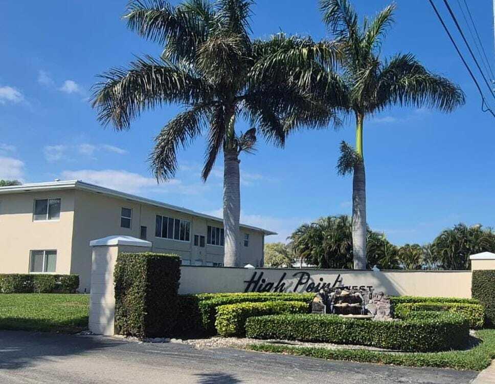 A beige two-story apartment building stands behind a landscaped sign with two tall palm trees — 310 Main Boulevard # C, Boynton Beach FL 33435, BOYNTON BEACH, FL