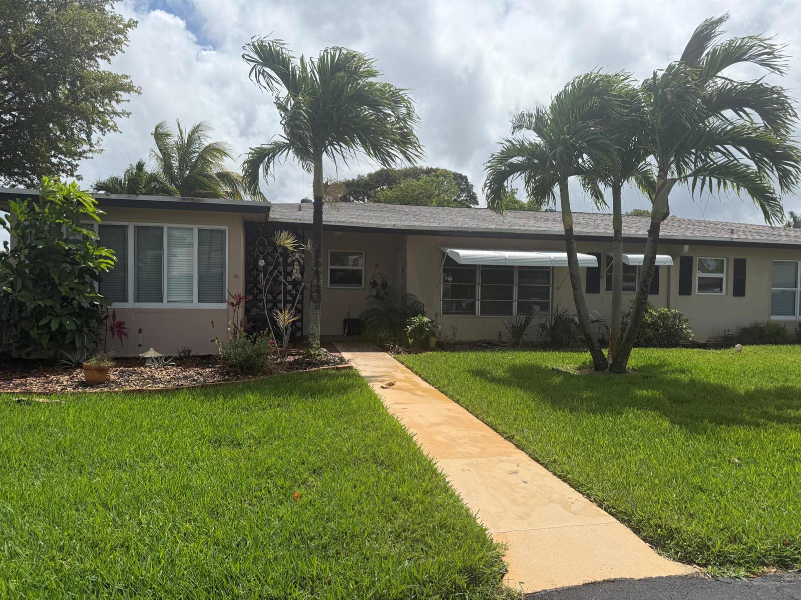 A single-story house with a concrete walkway, palm trees, and a green lawn — 1052 North Drive # B, Delray Beach FL 33445, DELRAY BEACH, FL