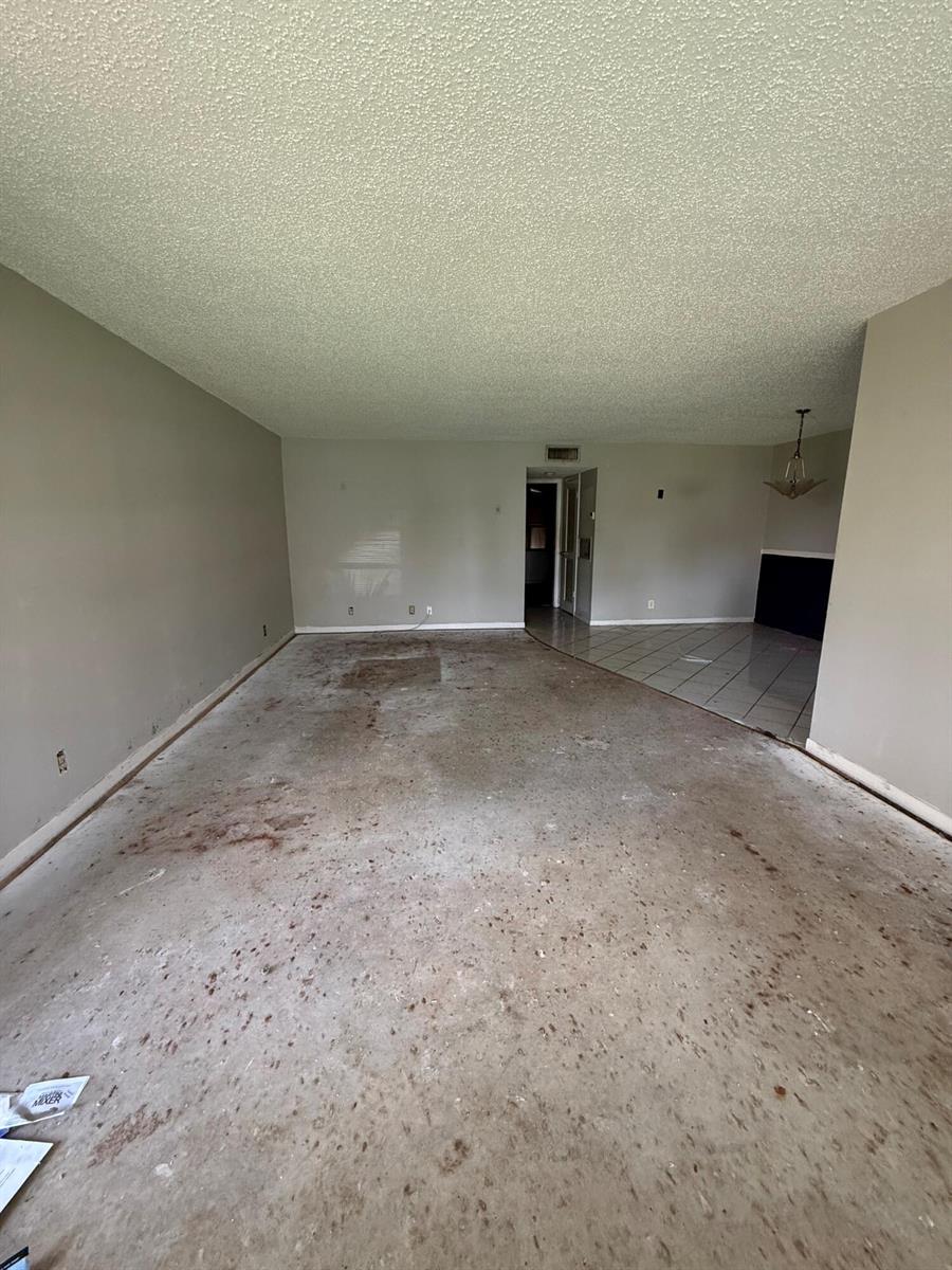 An empty room with bare concrete flooring, light gray walls, and a textured ceiling — 1052 North Drive # B, Delray Beach FL 33445, DELRAY BEACH, FL