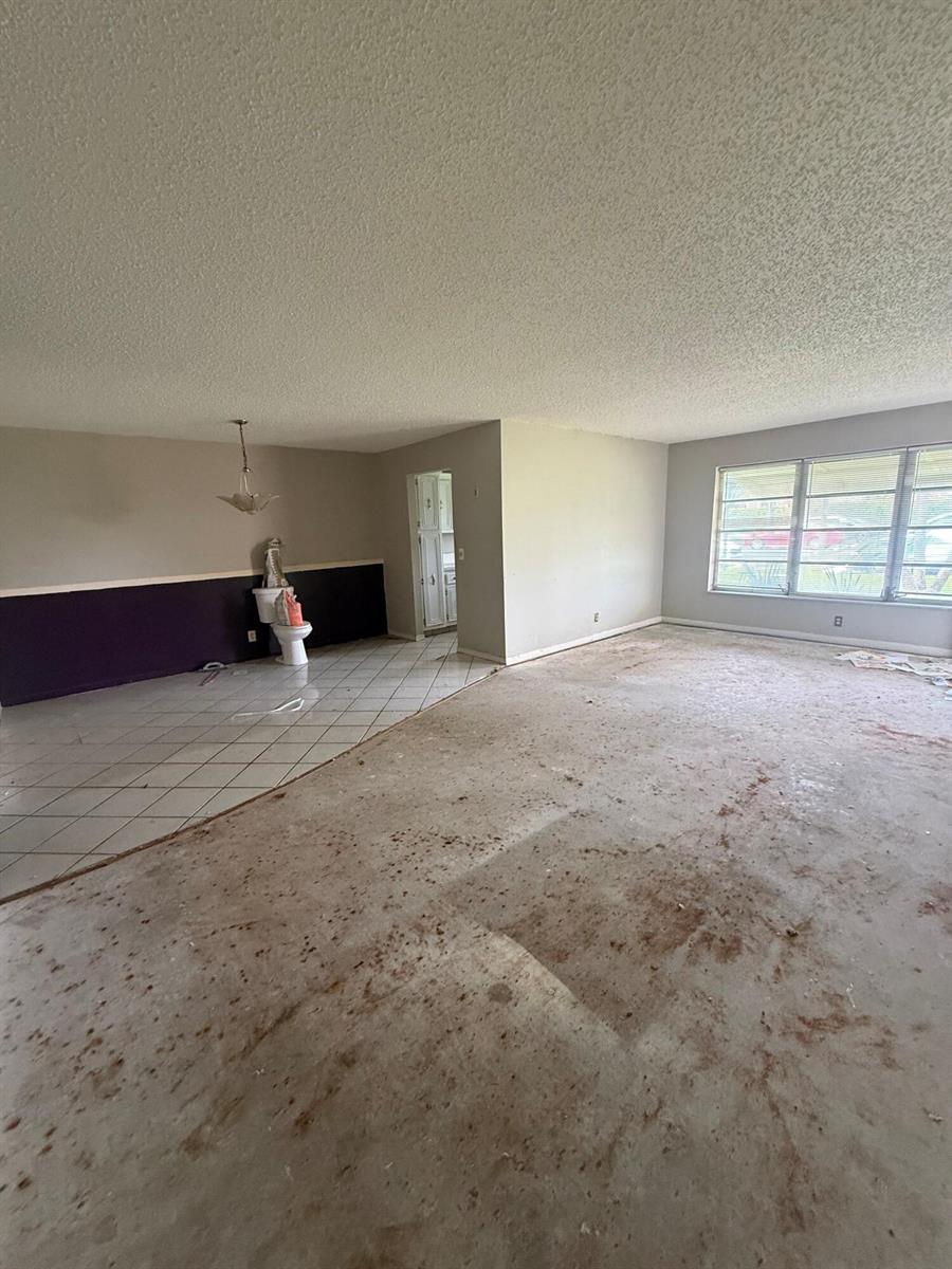 An open-concept room features a tiled area with a toilet and a carpeted living space — 1052 North Drive # B, Delray Beach FL 33445, DELRAY BEACH, FL