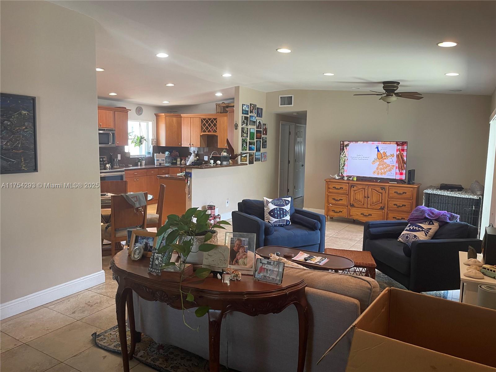 An open-concept living room features a kitchen, dining area, and two dark blue armchairs — 18986 SE Mayo Dr, Jupiter FL 33469, JUPITER, FL
