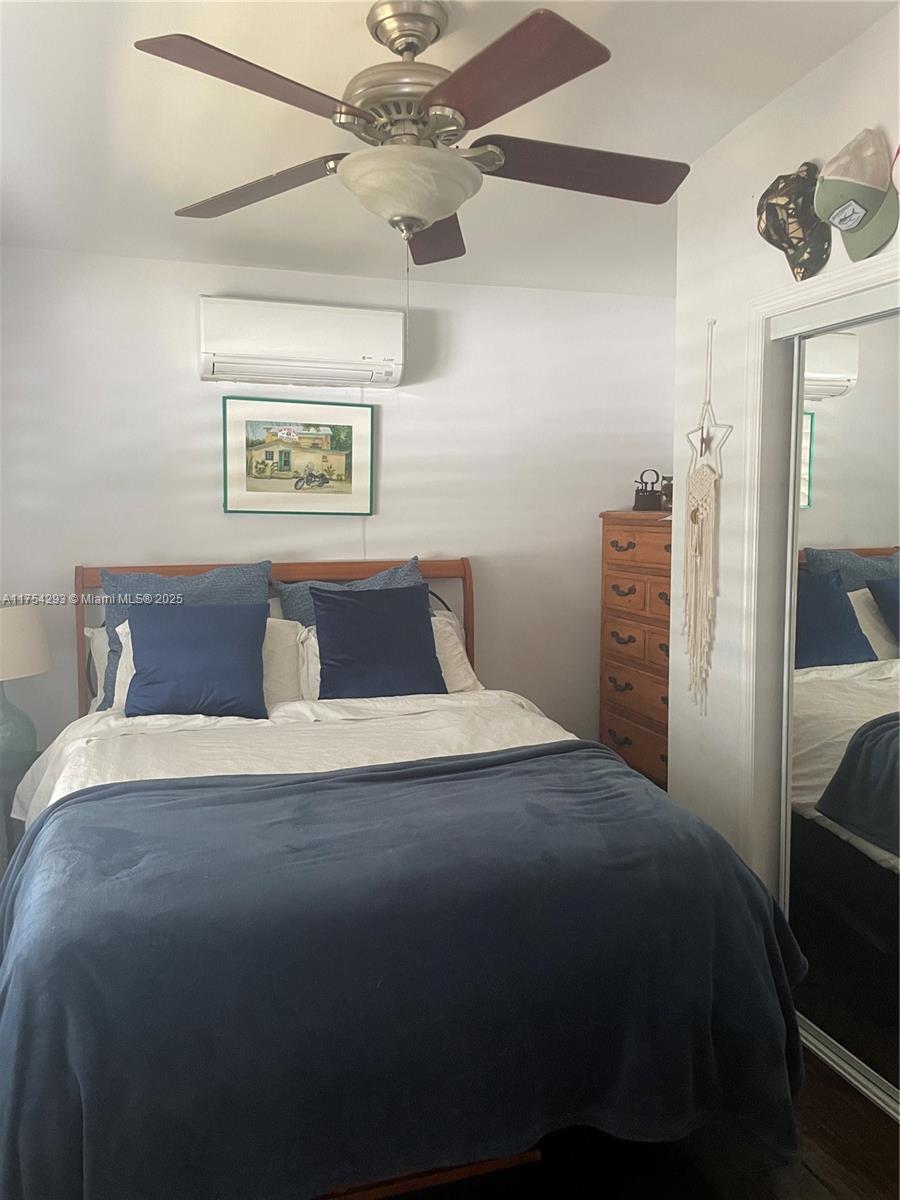 A bedroom features a bed with blue bedding, a ceiling fan, and a wooden dresser — 18986 SE Mayo Dr, Jupiter FL 33469, JUPITER, FL