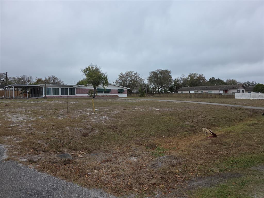 A large, vacant grassy lot sits in front of a single-story house with a carport — 2634 SOUTH DRIVE, CLEARWATER, FL