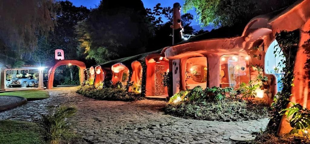 An exterior view of a unique, organic-style house with curved walls and illuminated arched windows — 1 CIGARRALES DE SANTA TERESA, An, An