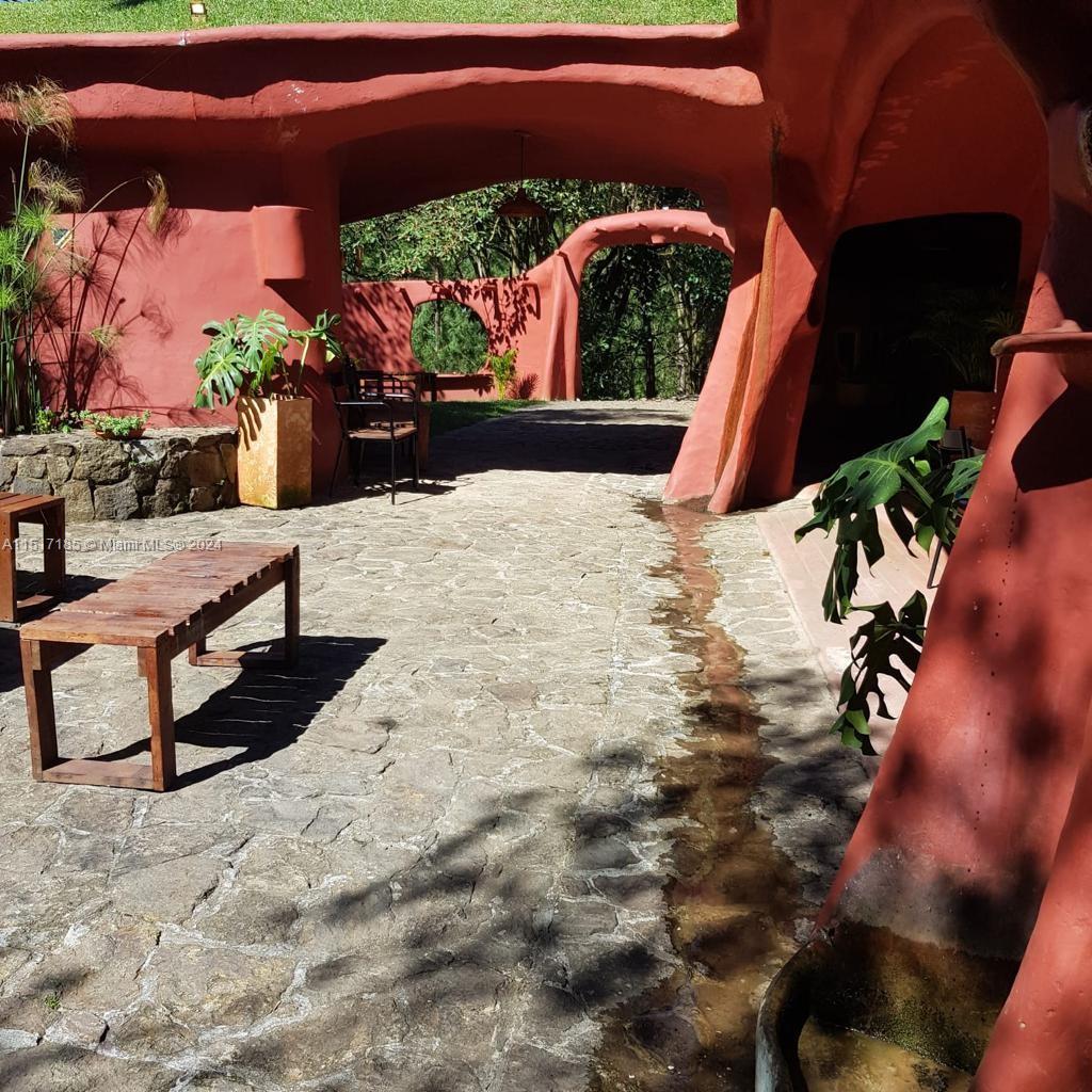 An outdoor stone patio features a narrow water channel and terracotta-colored arched architectural structures — 1 CIGARRALES DE SANTA TERESA, An, An