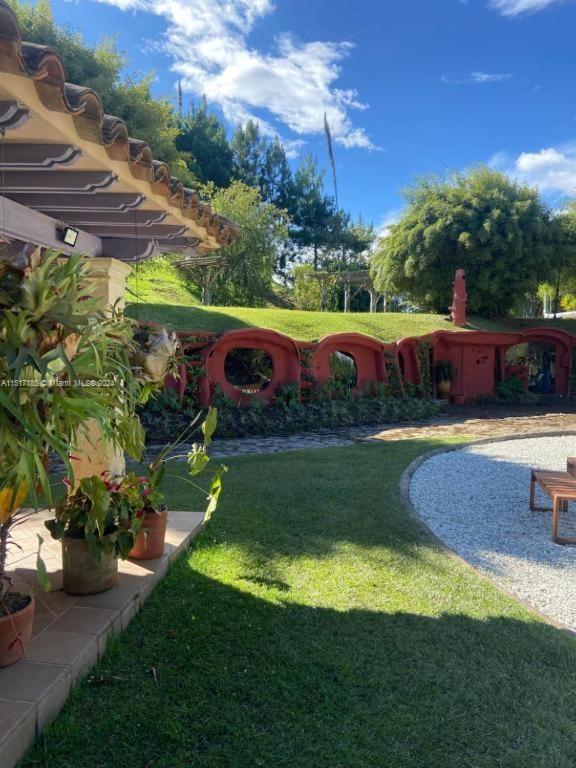 A patio overlooks a grassy yard with a distinctive red, arched decorative wall — 1 CIGARRALES DE SANTA TERESA, An, An