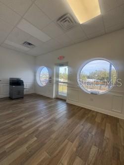 An office room with wood-look flooring, a printer, and two circular windows — 4908 DENVER STREET, TAMPA, FL
