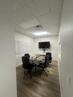 A small office features a conference table, four black chairs, a wall-mounted television, and flooring — 4908 DENVER STREET, TAMPA, FL
