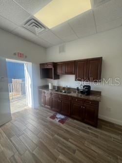A kitchen area features dark wood cabinets, a sink, and light-colored wood-look tile flooring — 4908 DENVER STREET, TAMPA, FL