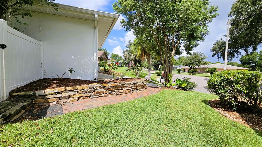 A stone retaining wall borders a brick walkway next to a white house exterior — 410 BROADVIEW AVENUE, ALTAMONTE SPRINGS, FL