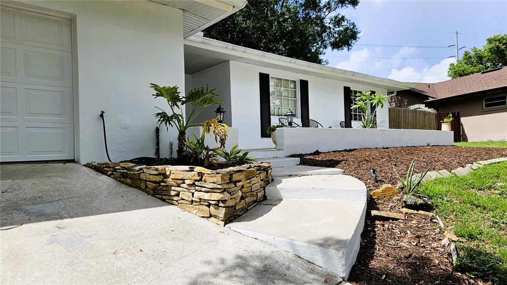 A white house exterior features a stone planter, concrete steps, and a garage door — 410 BROADVIEW AVENUE, ALTAMONTE SPRINGS, FL