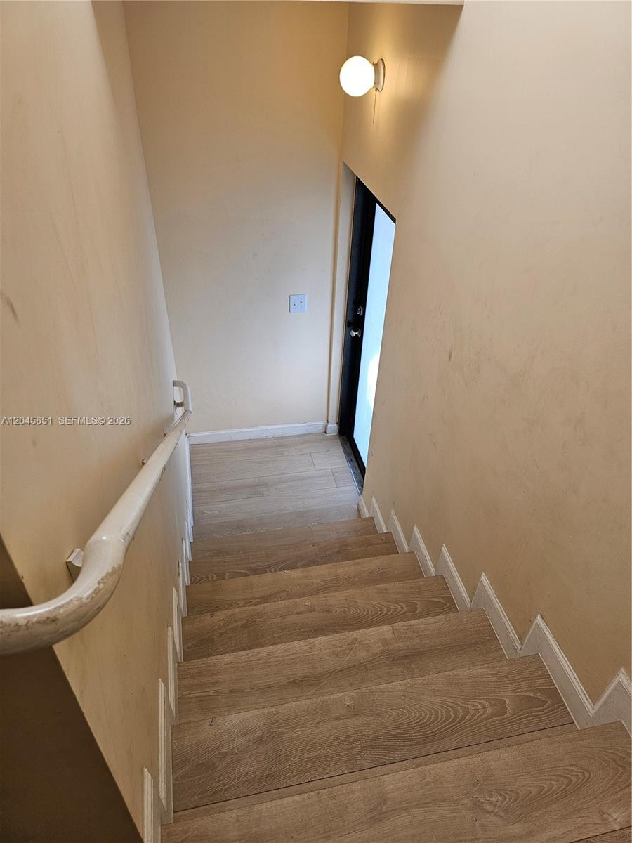 A wooden staircase leads down to a doorway with a light fixture above — 10455 SW 179th St # 1, Miami FL 33157, MIAMI, FL