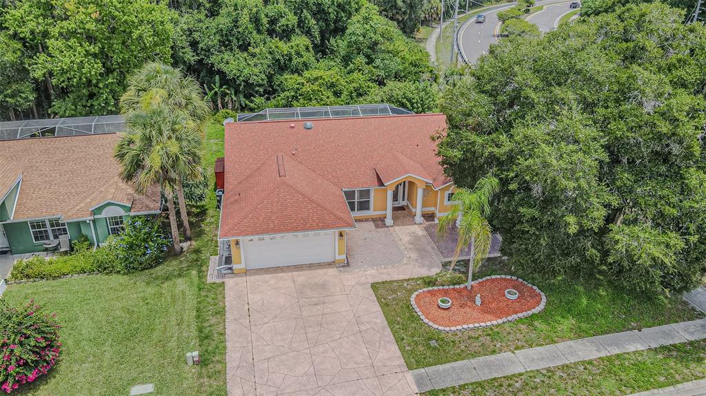 An aerial view shows a single-story house with a red roof, garage, and pool enclosure — 7715 CYPRESS TRACE COURT, NEW PORT RICHEY, FL