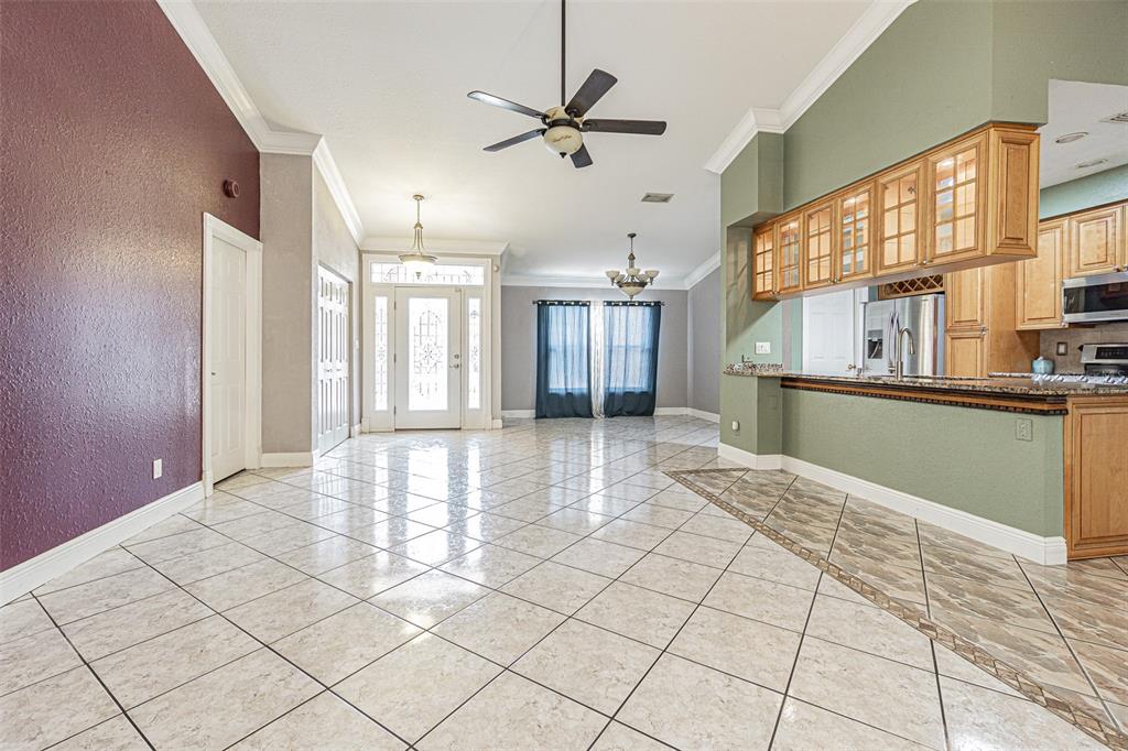A spacious living area with tile flooring, a ceiling fan, and an open kitchen — 7715 CYPRESS TRACE COURT, NEW PORT RICHEY, FL