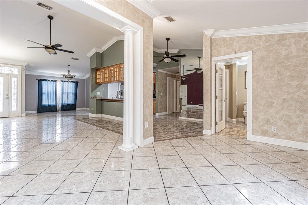 An open-concept living area features tiled floors, a decorative column, and a view into the kitchen — 7715 CYPRESS TRACE COURT, NEW PORT RICHEY, FL