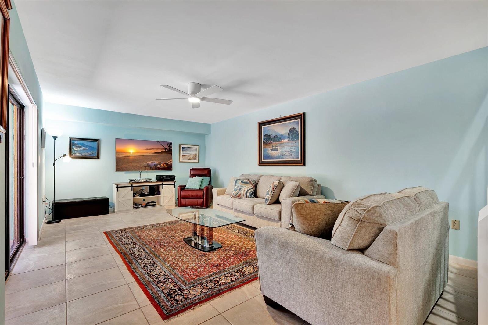 A living room features light blue walls, a beige sofa, a glass coffee table, and tile flooring — 3016 30th Court, Jupiter FL 33477, JUPITER, FL