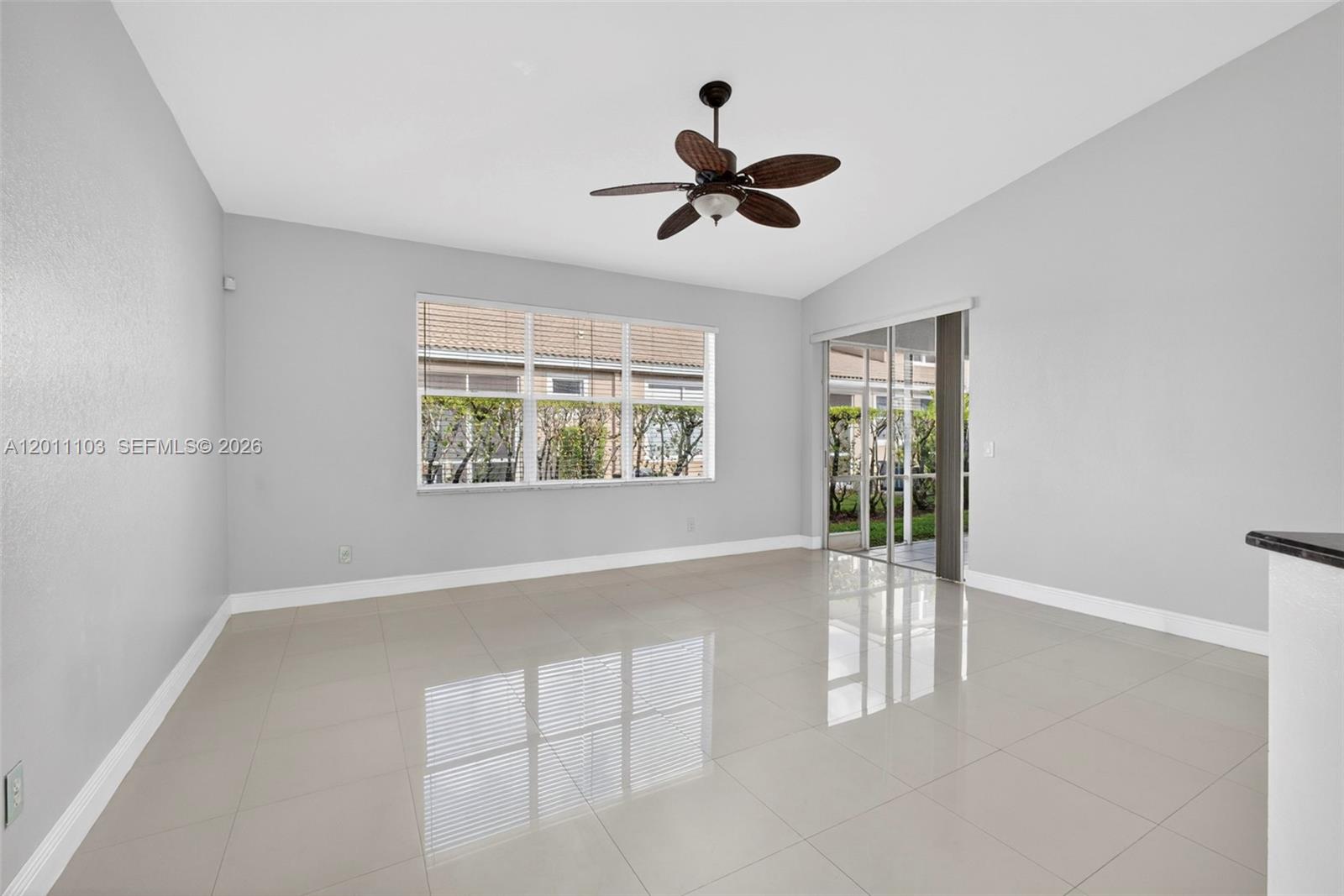 A bright room features light gray walls, large windows, sliding glass doors, and tiled flooring — 2151 Umbrella Cay, West Palm Beach FL 33411, WEST PALM BEACH, FL