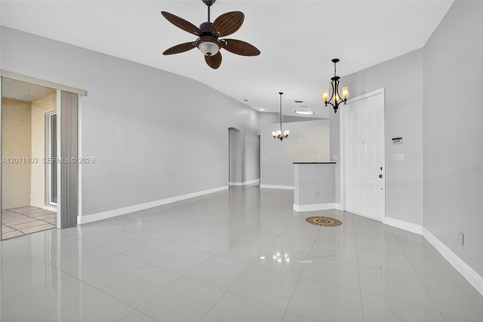 An open living area features light gray walls, white tile flooring, and two hanging light fixtures — 2151 Umbrella Cay, West Palm Beach FL 33411, WEST PALM BEACH, FL