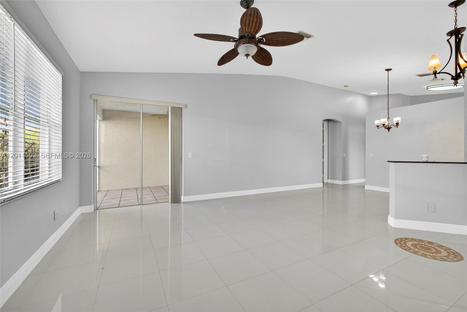 A bright, open-concept living area features light gray walls, white tile flooring, and a ceiling fan — 2151 Umbrella Cay, West Palm Beach FL 33411, WEST PALM BEACH, FL
