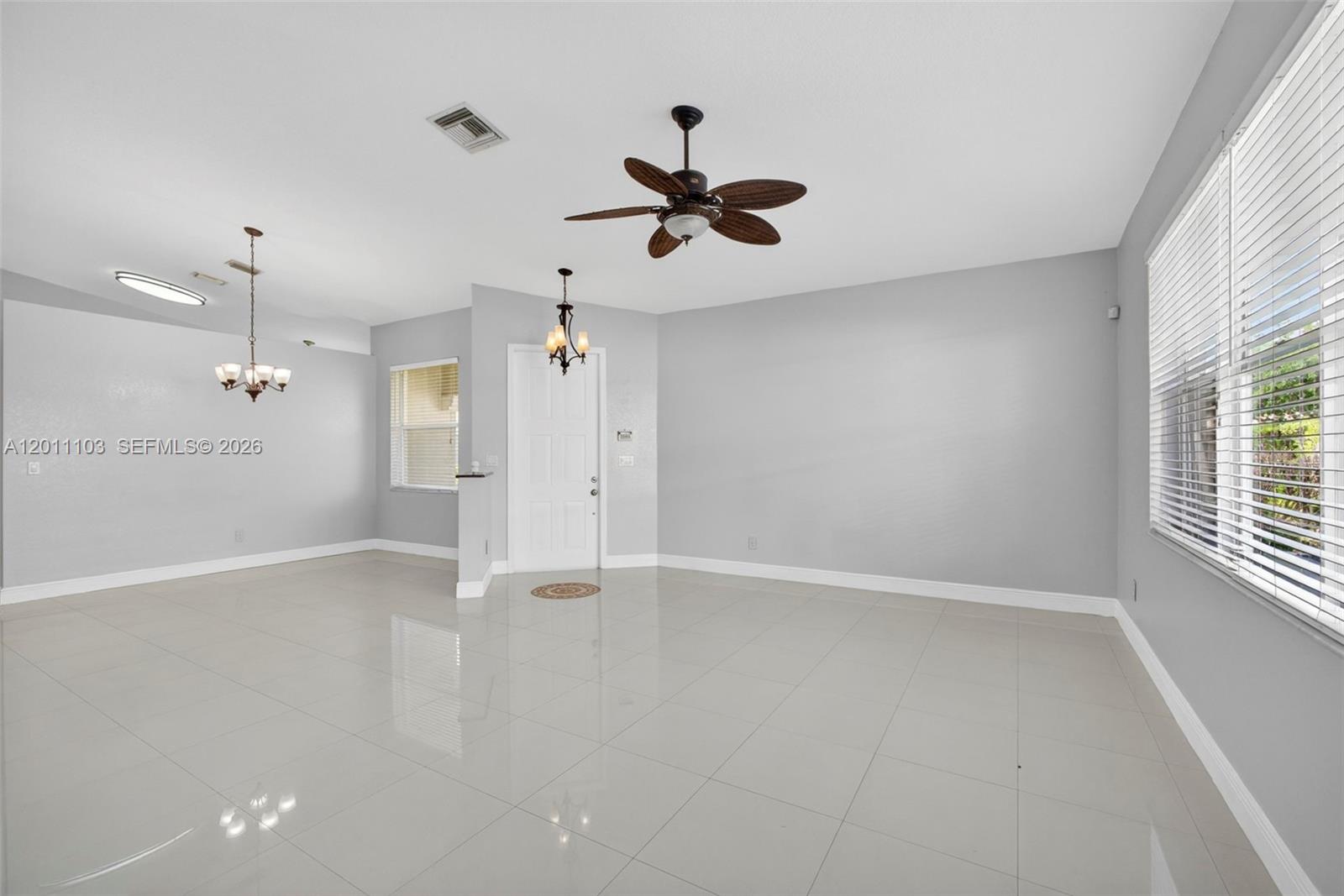 A bright, open-concept living area features light gray walls, white tile flooring, and a ceiling fan — 2151 Umbrella Cay, West Palm Beach FL 33411, WEST PALM BEACH, FL