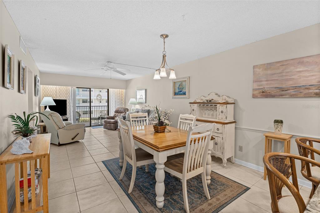 A dining area with a wooden table and chairs sits adjacent to a living room — 4100 OCEAN BEACH BOULEVARD UNIT 206, COCOA BEACH, FL