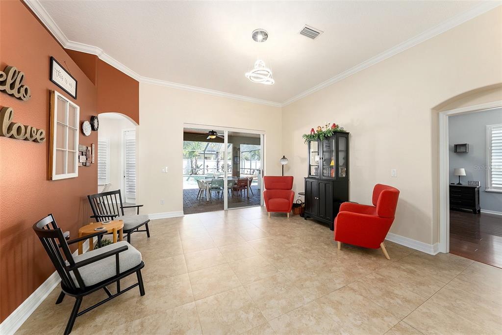 A living room with tile floors, red armchairs, black chairs, and a sliding glass door — 19328 AUTUMN WOODS AVENUE, TAMPA, FL