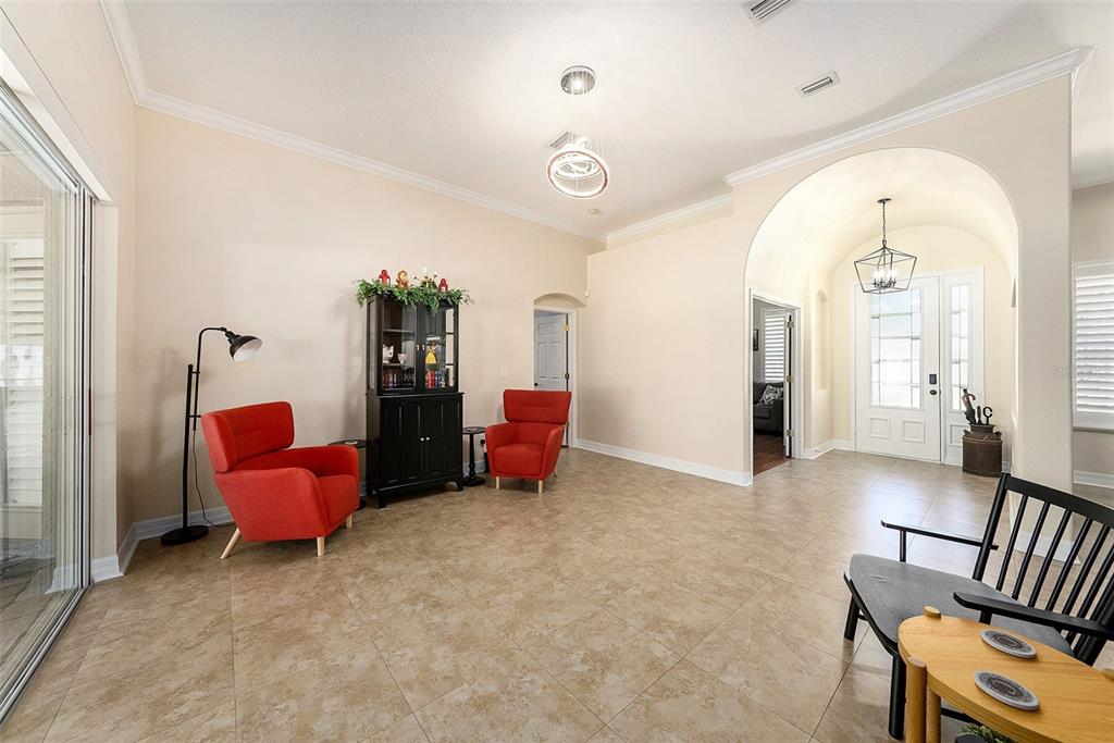 A spacious living area features tile flooring, two red armchairs, and an arched entryway — 19328 AUTUMN WOODS AVENUE, TAMPA, FL