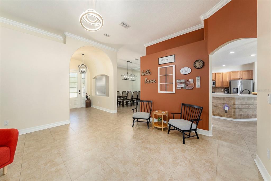 A tiled entryway features a rust-colored accent wall with two chairs and a dining area — 19328 AUTUMN WOODS AVENUE, TAMPA, FL