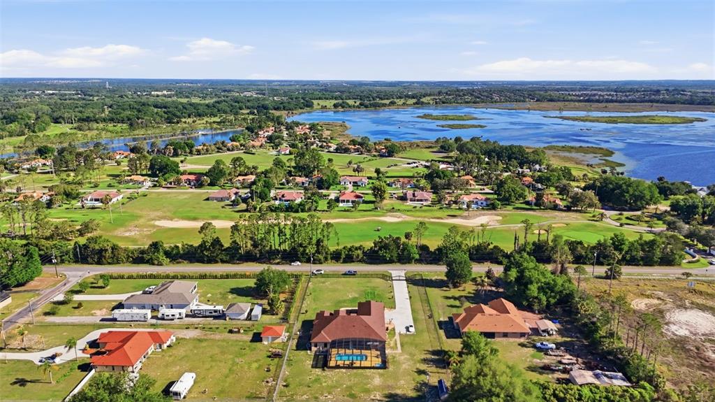 An aerial view shows several houses with pools near a large lake and golf course — 13429 MONTEVISTA ROAD, CLERMONT, FL