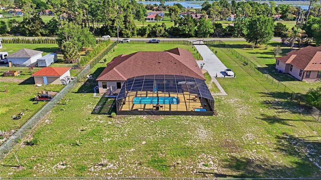 An aerial view of a house with a screened-in pool and a large fenced yard — 13429 MONTEVISTA ROAD, CLERMONT, FL