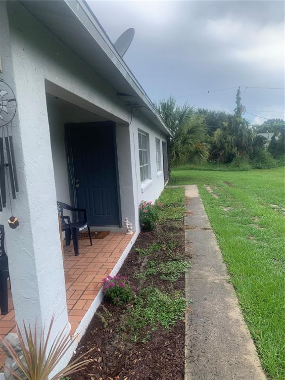 A side view of a house exterior featuring a brick porch, walkway, and landscaping — 1674 NE FLORIDIAN CIRCLE, ARCADIA, FL
