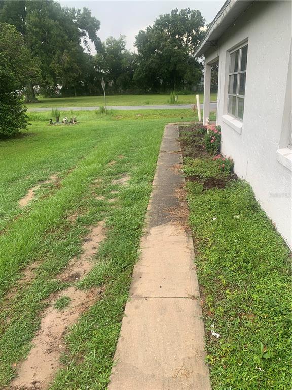 A concrete walkway runs along the side of a white house next to a lawn — 1674 NE FLORIDIAN CIRCLE, ARCADIA, FL