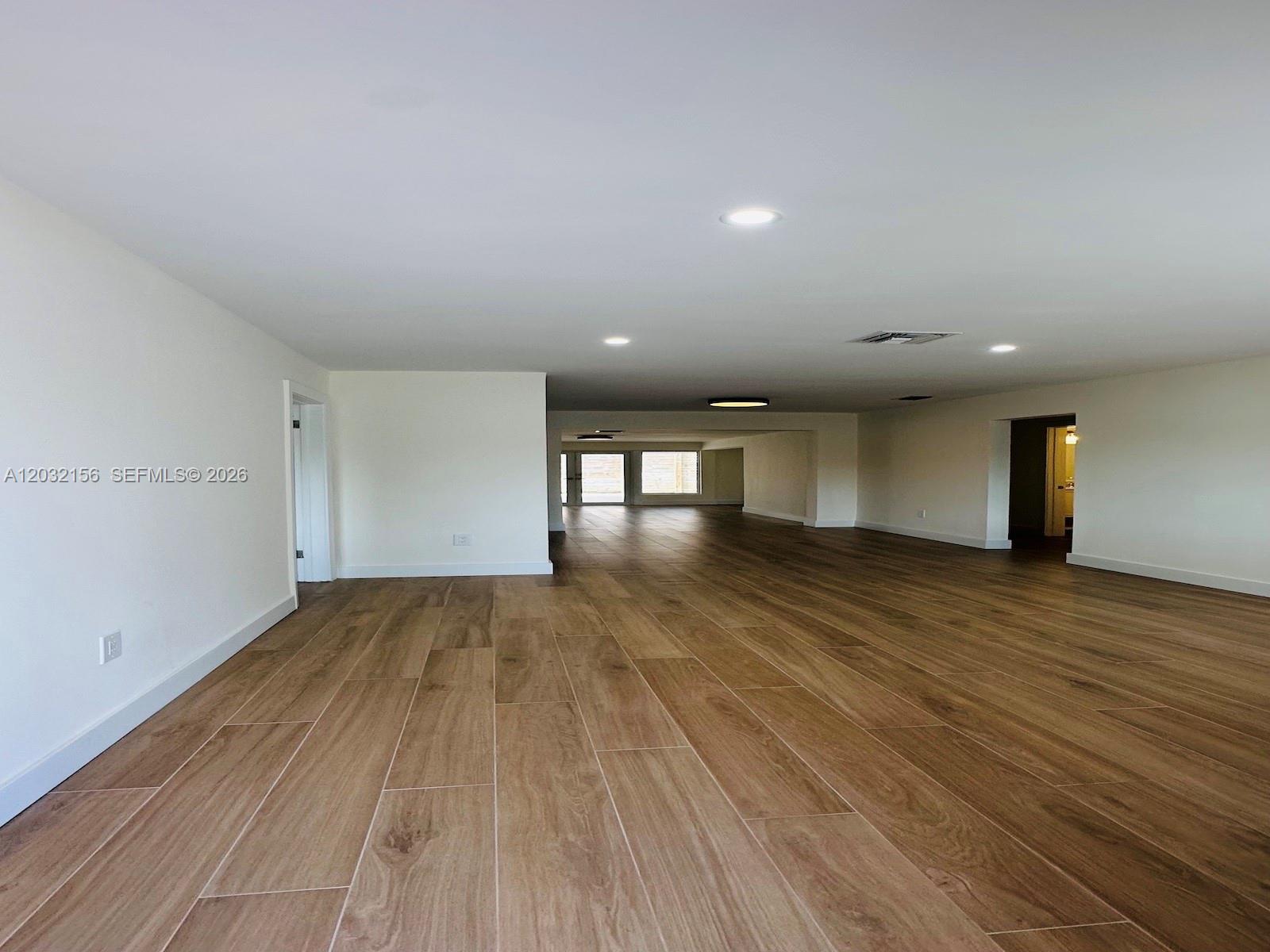 An expansive, unfurnished room features white walls, recessed lighting, and light wood-look tile flooring — 4120 SW 69 Ave, Miami FL 33155, MIAMI, FL