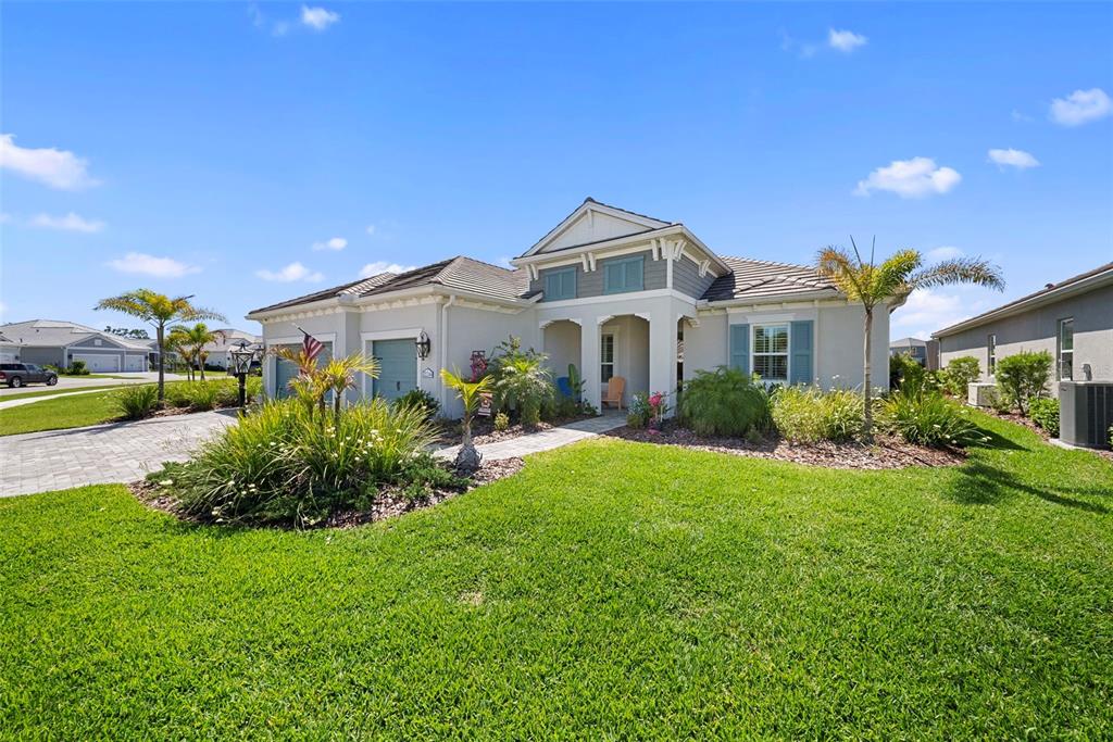 A single-story suburban house with a paved driveway, green lawn, and blue shutters — 21244 HOLMES CIRCLE, VENICE, FL