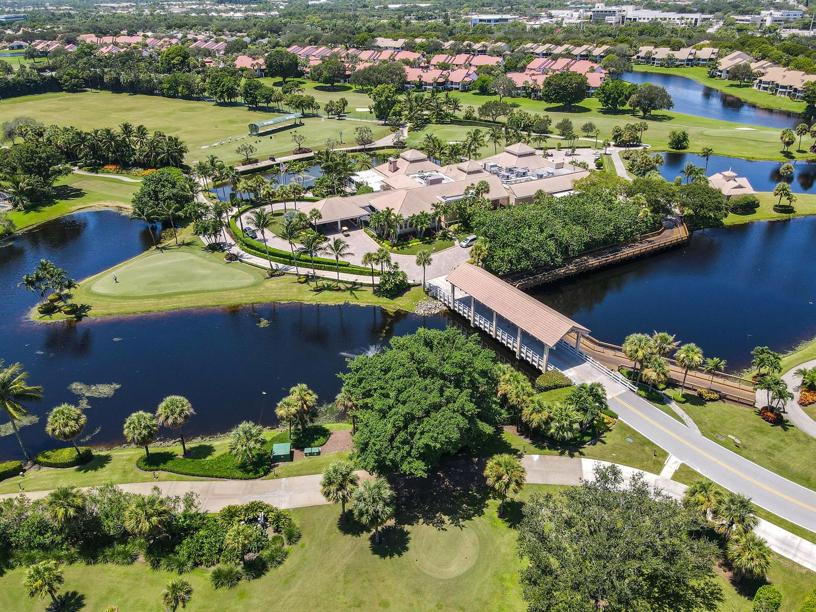 An aerial view shows a clubhouse, a covered bridge, and a golf course with ponds — 3322 Casseekey Island Road # 302, Jupiter FL 33477, JUPITER, FL