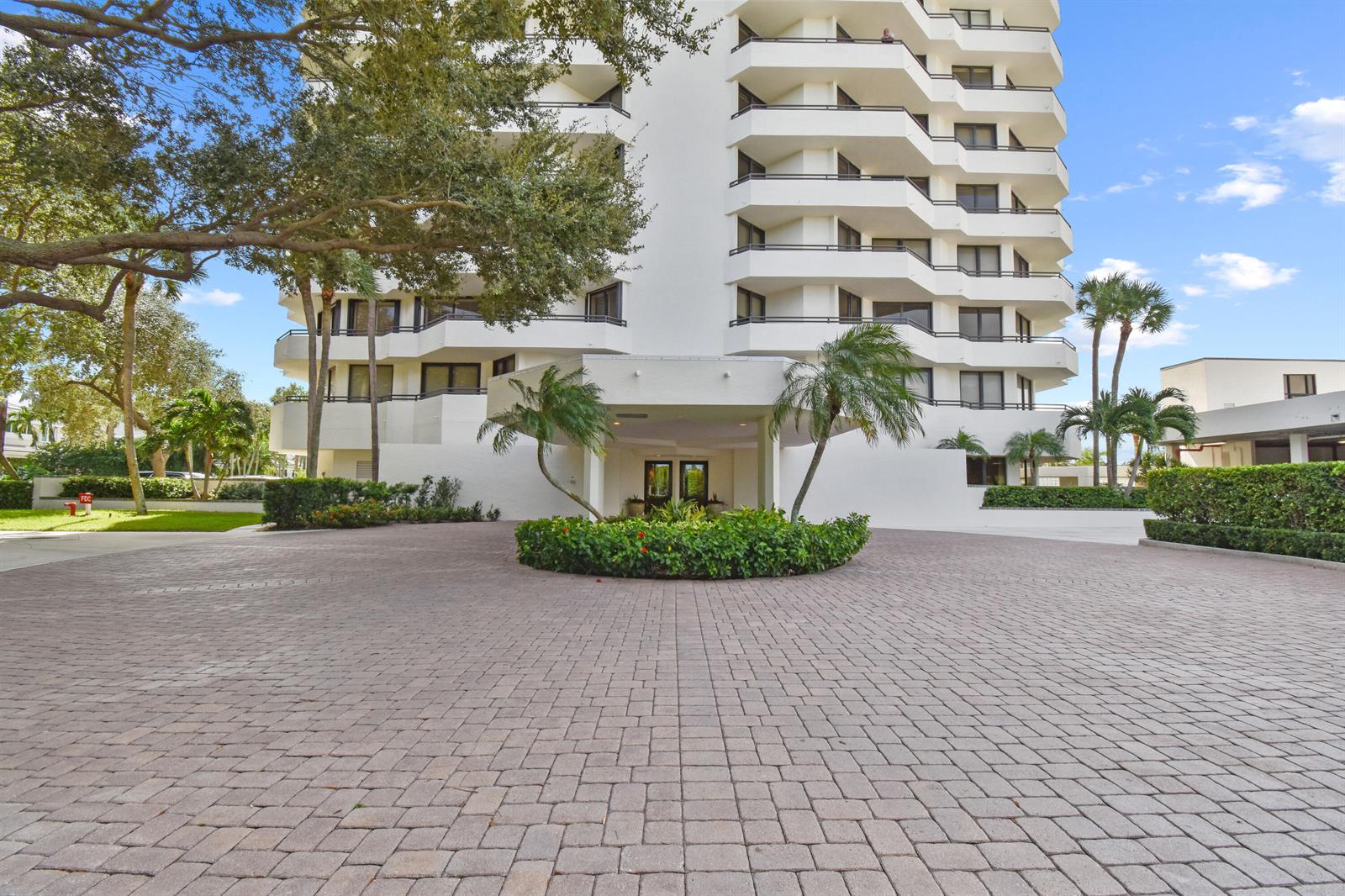 A multi-story white residential building features a paved circular driveway and a covered entrance — 3322 Casseekey Island Road # 302, Jupiter FL 33477, JUPITER, FL