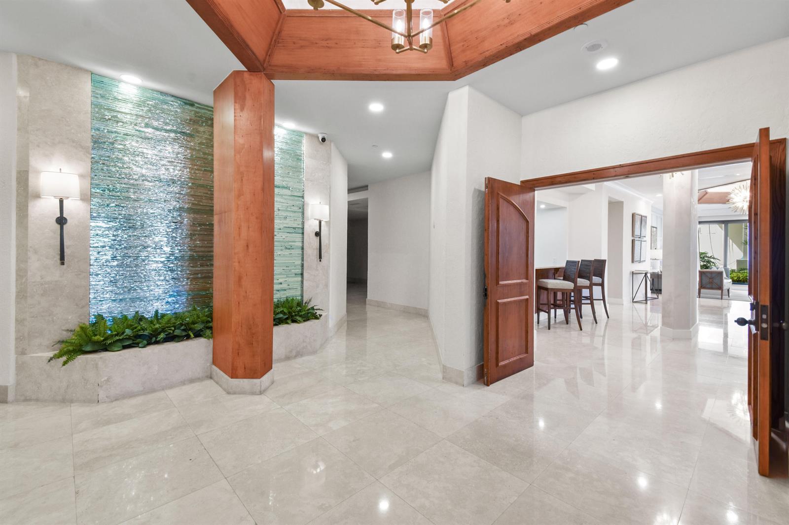 A bright foyer features marble floors, a wooden ceiling detail, and a glass water feature — 3322 Casseekey Island Road # 302, Jupiter FL 33477, JUPITER, FL