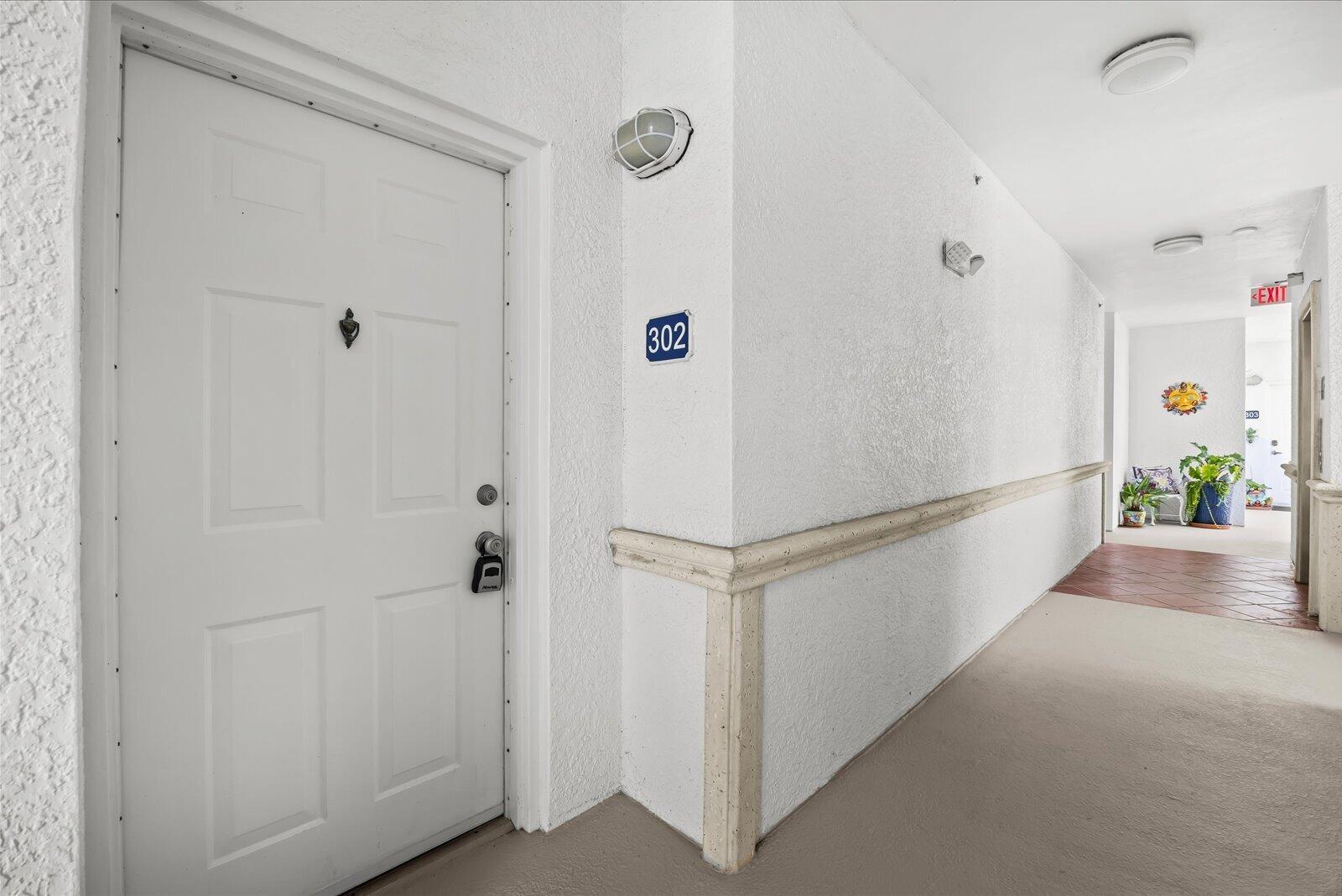 A white apartment door labeled 302 is situated in a hallway with beige carpeting — 715 NW Flagler Avenue # 302, Stuart FL 34994, STUART, FL