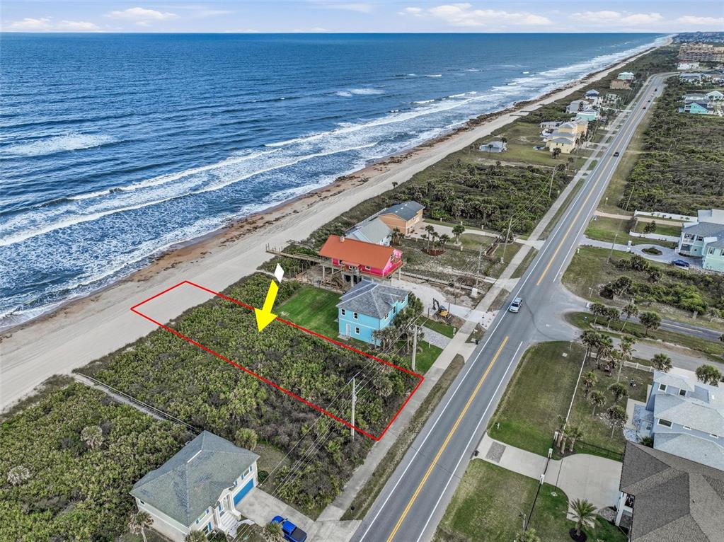 An aerial view shows a vacant coastal lot outlined in red next to beach houses — 7103 N OCEAN SHORE BOULEVARD, PALM COAST, FL