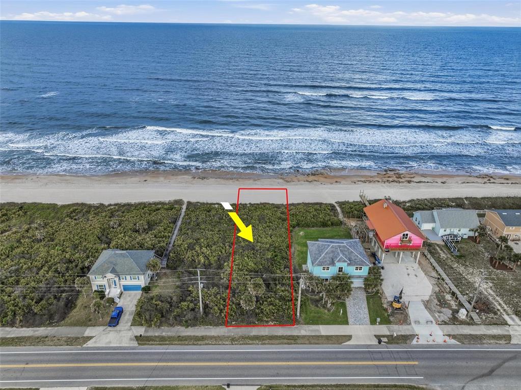 An aerial view shows a vacant oceanfront lot outlined in red between two existing houses — 7103 N OCEAN SHORE BOULEVARD, PALM COAST, FL