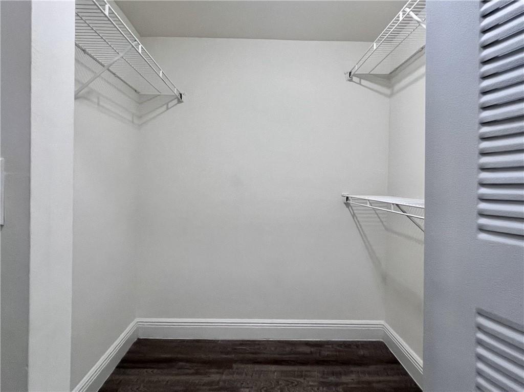 A small walk-in closet features white walls, dark wood-look flooring, and white wire shelving — 18335 NW 68 Avenue # 110, Hialeah FL 33015, HIALEAH, FL