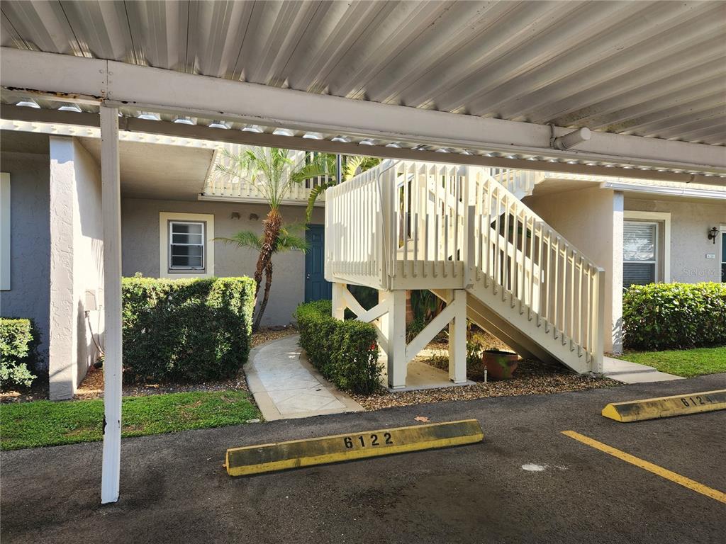 A covered parking space sits in front of a building with an exterior wooden staircase — 6122 7TH AVENUE W, BRADENTON, FL