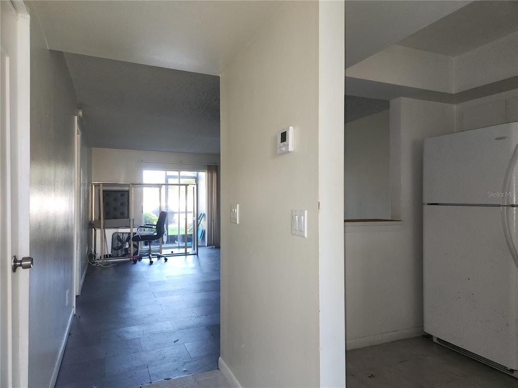 A view from a hallway looking into a living area with a sliding glass door — 6122 7TH AVENUE W, BRADENTON, FL