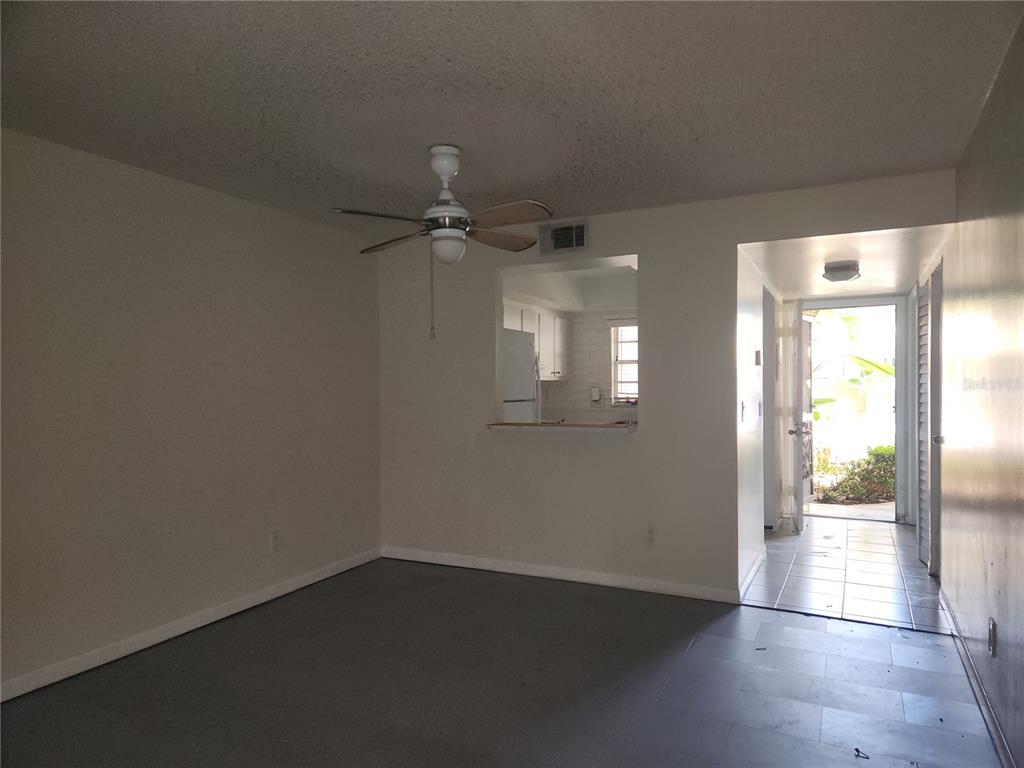 An empty room with a ceiling fan, a kitchen pass-through window, and an open doorway — 6122 7TH AVENUE W, BRADENTON, FL