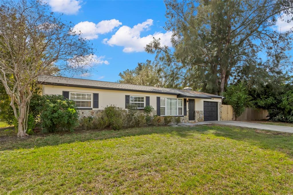 A single-story house with a stone facade, dark shutters, and a driveway under a blue sky — 1524 ARIZONA AVENUE NE, ST PETERSBURG, FL
