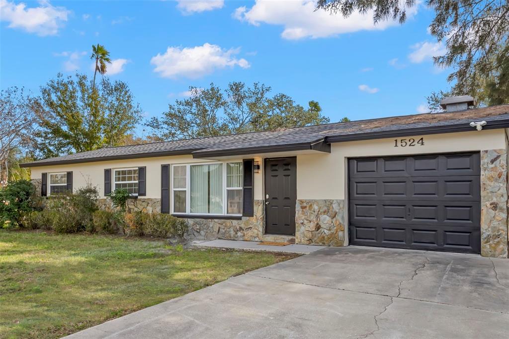 A single-story house with a stone facade, dark shutters, and a one-car garage — 1524 ARIZONA AVENUE NE, ST PETERSBURG, FL